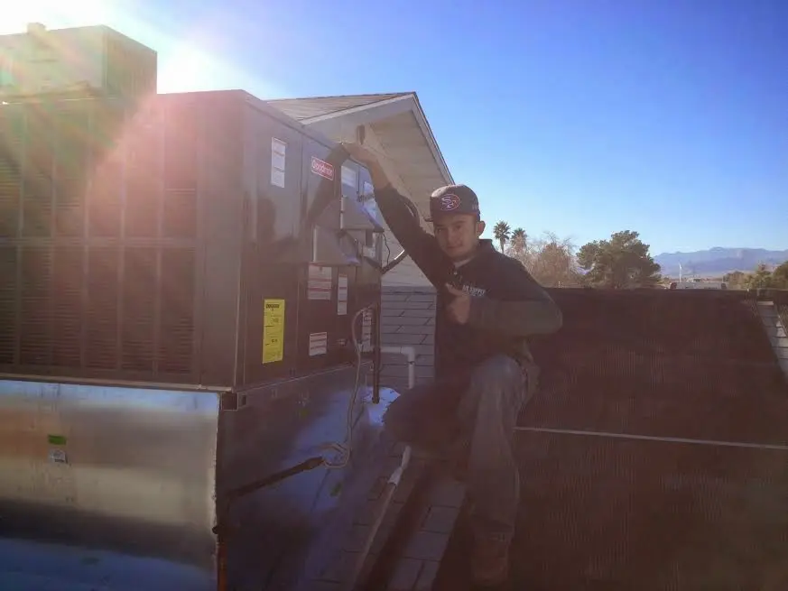HVAC technician performing Heat Pump Repair on a rooftop unit in De Witt